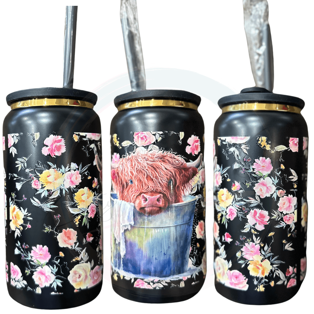 this 16oz popcan style tumbler has a lid to resemble the look o f a pop can. This ever so cute Highland is sitting in a bucket full of water with its face on the edge with flowers all around the tumbler. 