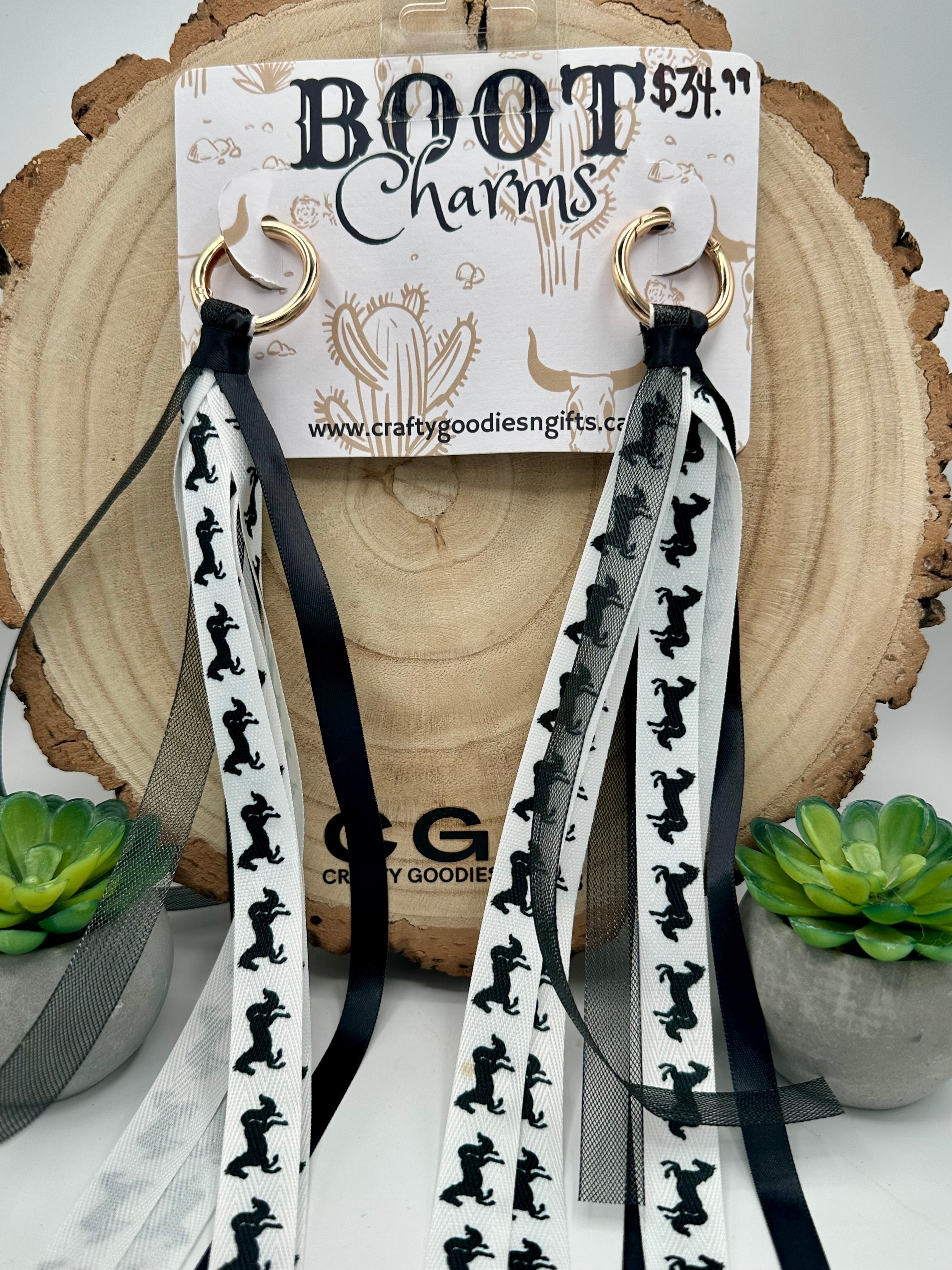 A pair of boot charms with long black and white  horse patterned ribbons and gold-tone rings.